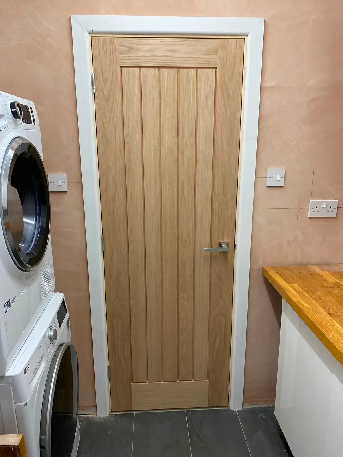 Oak boarded door fitted to a utility room, hung in a painted frame beside an oak worktop.