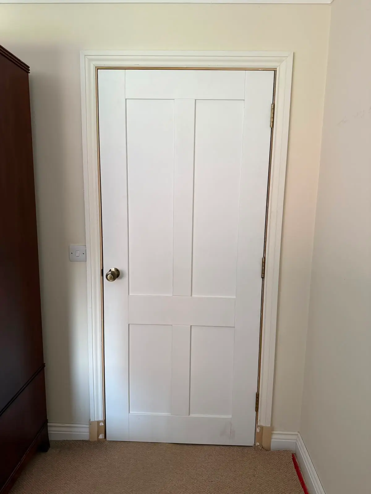 White painted four-panel internal door with a brass knob and brass butt hinges.