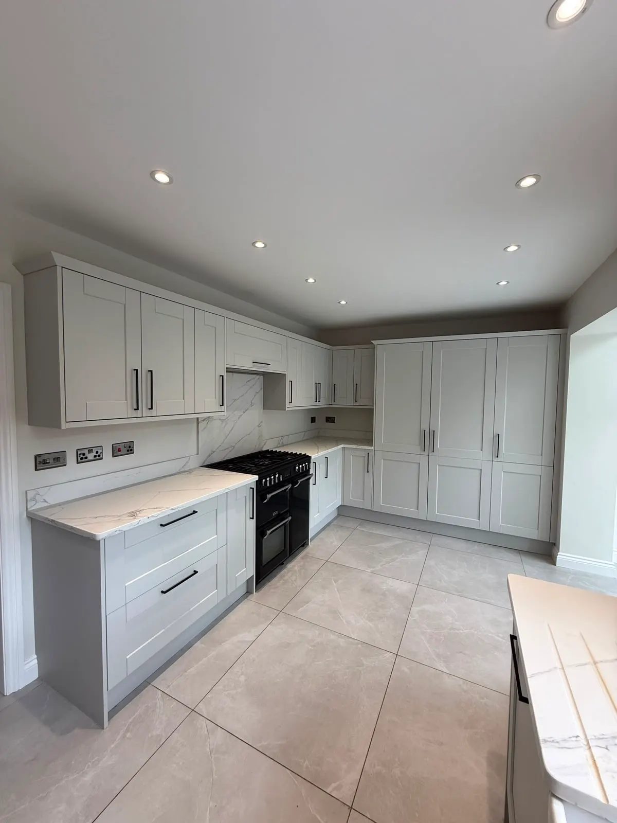 Shaker kitchen painted soft grey, with a range cooker set into a chimney breast recess.