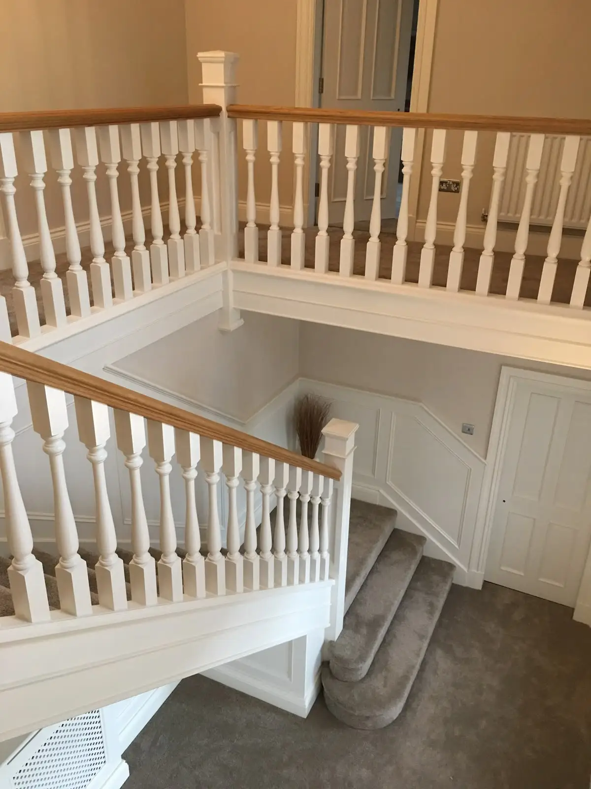 Galleried landing with white turned spindles and an oak handrail returning around the stairwell.