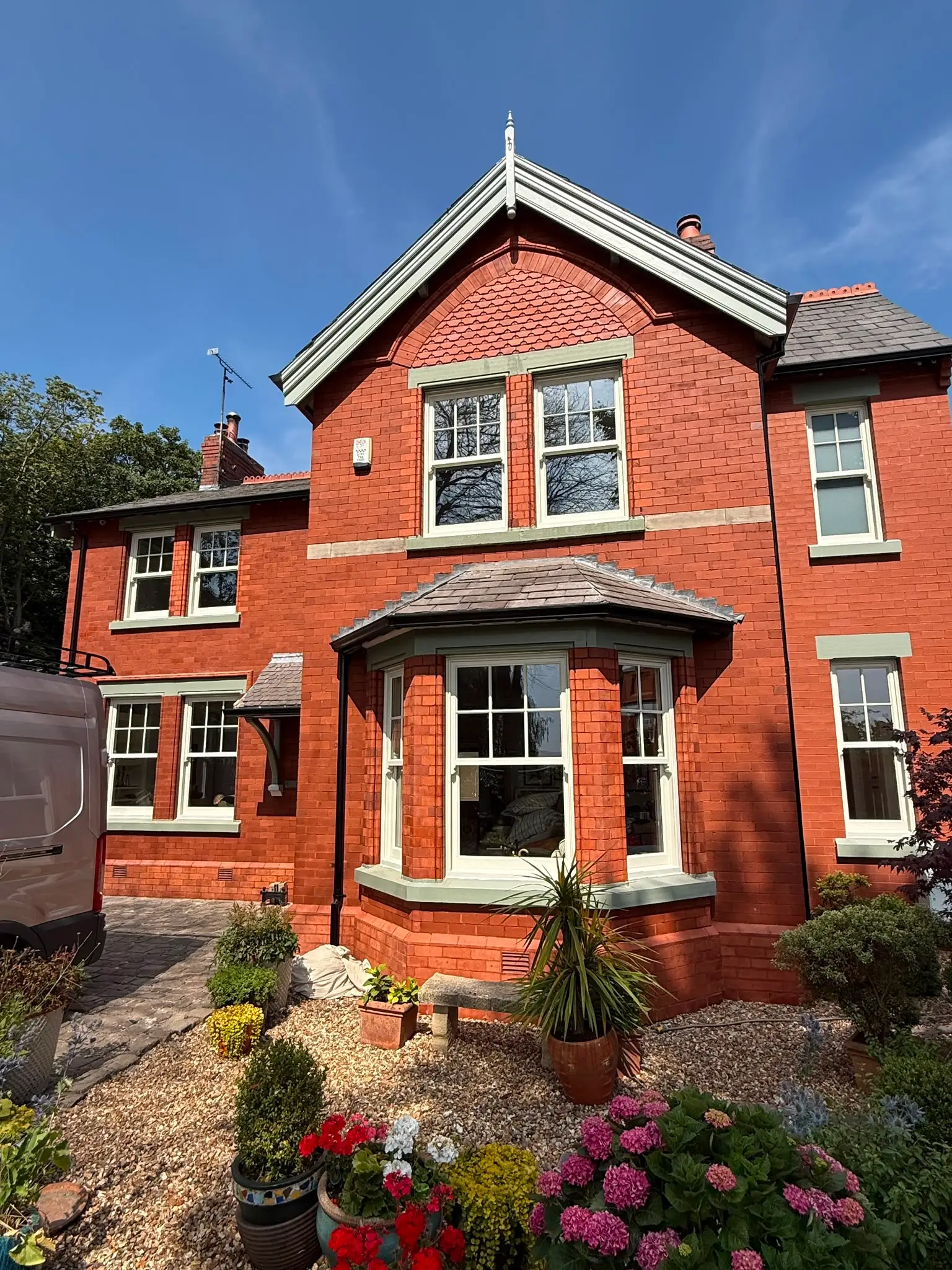 Front elevation of a red brick house with sash windows throughout, including a tiled bay and a gabled upper window.